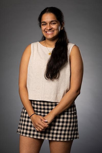 Ananditha Rahunath wears a plaid skirt and white tank top smiling at the camera.