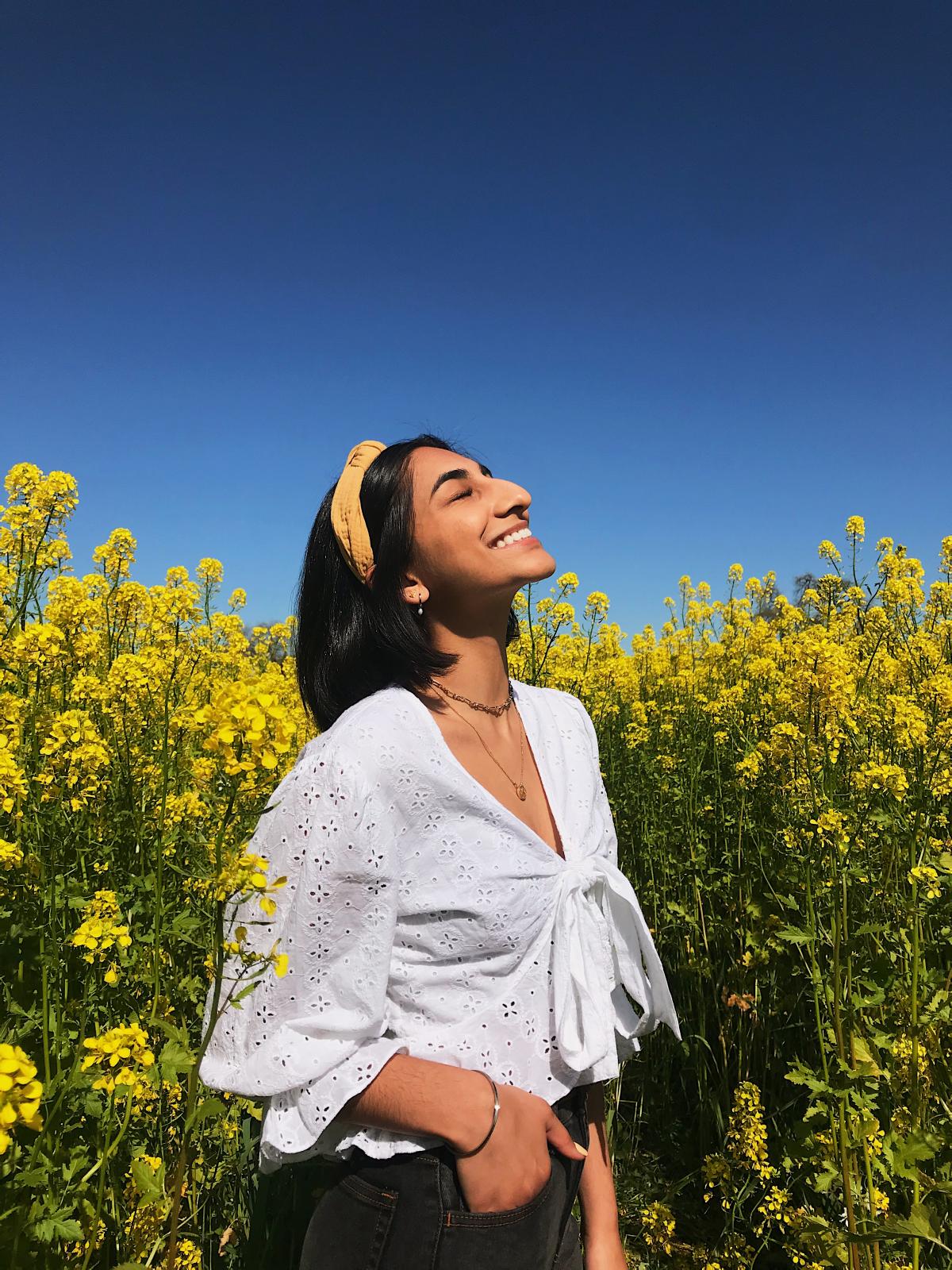 Portrait of Avneet Bhullar smiling in a field of flowers 