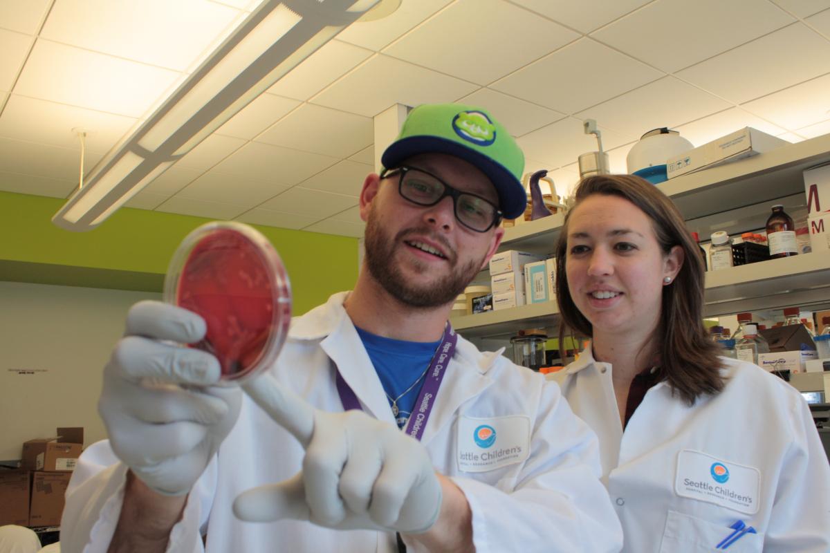Photo of Jay and a fellow student looking at bacteria cultures
